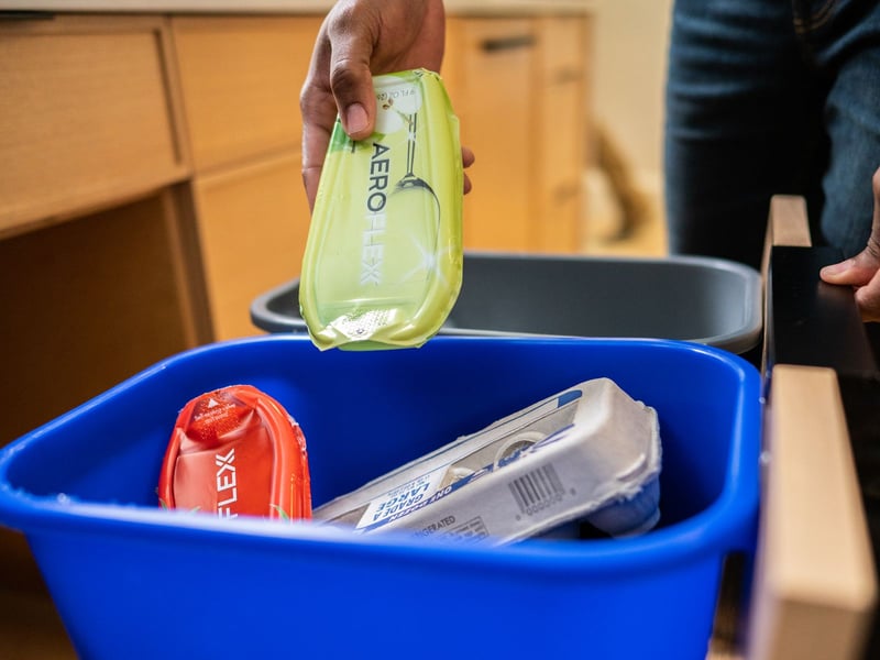 Person putting AeroFlexx in blue recycling bin