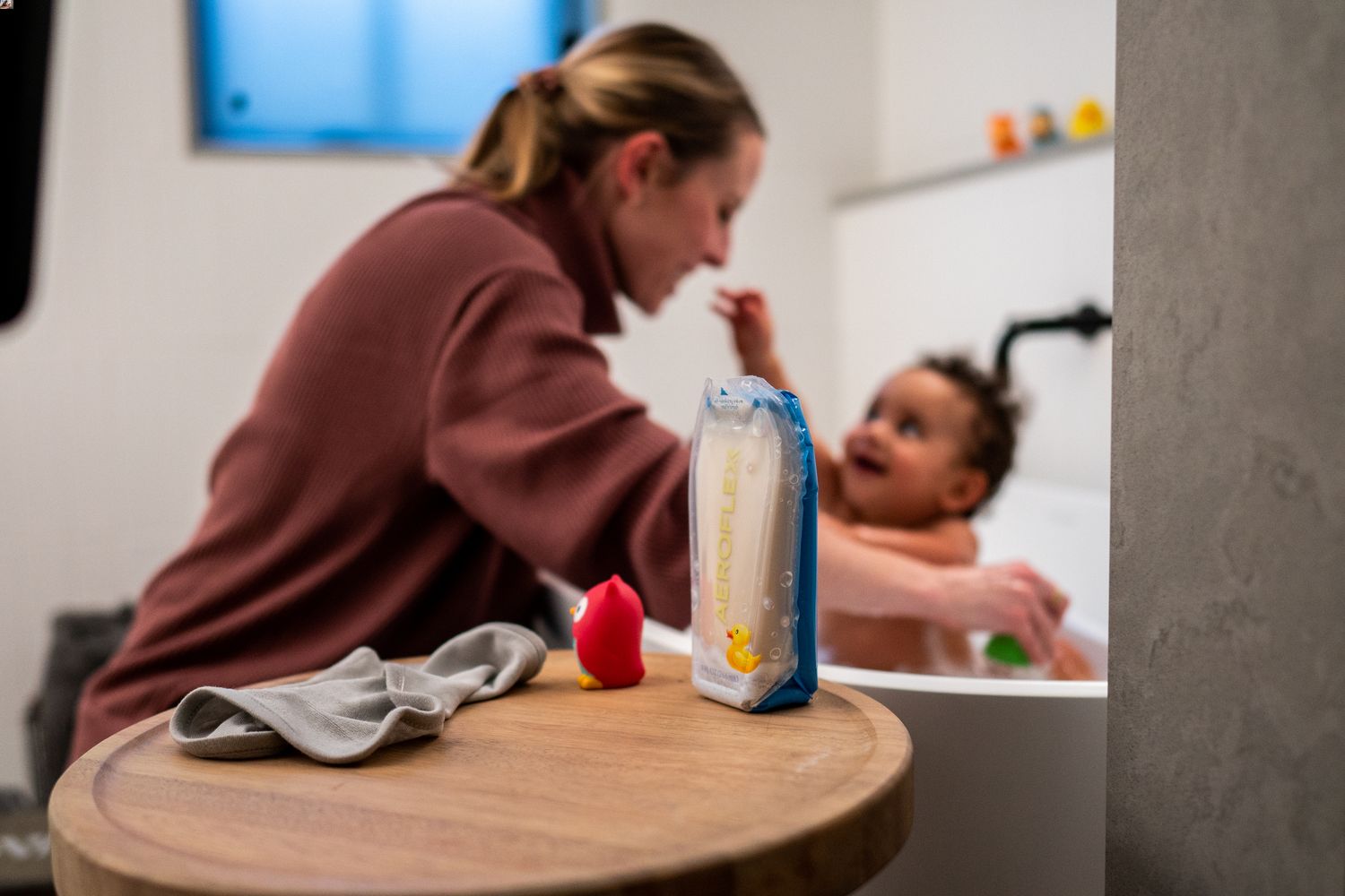 Woman bathing a baby with an AeroFlexx Pak of baby soap