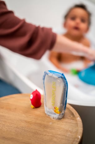 Person bathing a baby with an AeroFlexx Pak of baby soap