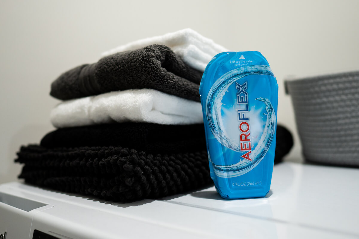AeroFlexx Pak with laundry detergent sitting next to folded towels