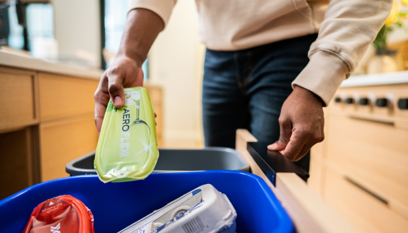 Person putting AeroFlexx in blue recycling bin