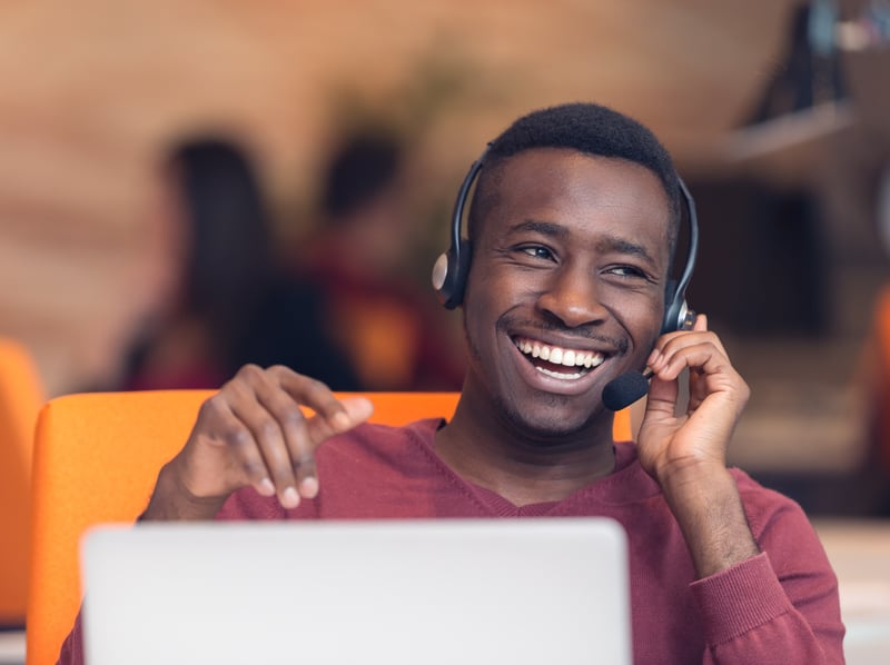 Man sitting with a headset on, talking to a customer on the phone